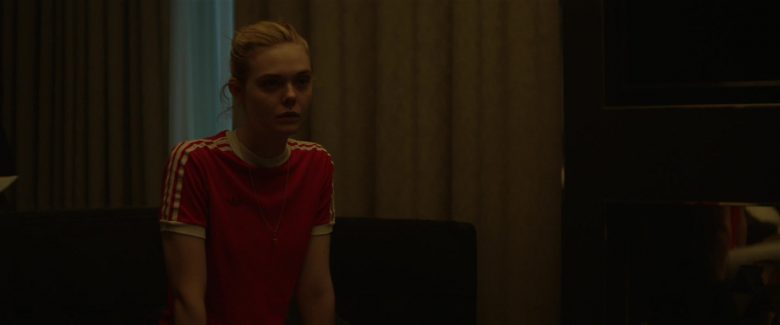 Elle Fanning standing in front of a curtain