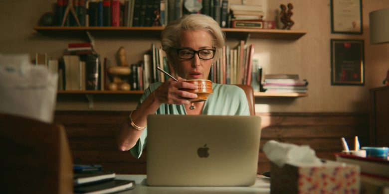 Gillian Anderson sitting at a table using a laptop