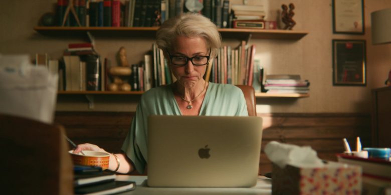 Gillian Anderson sitting at a table using a laptop computer