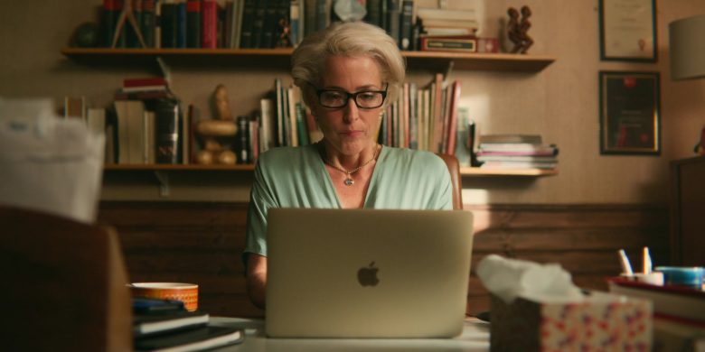 Gillian Anderson sitting at a table using a laptop computer