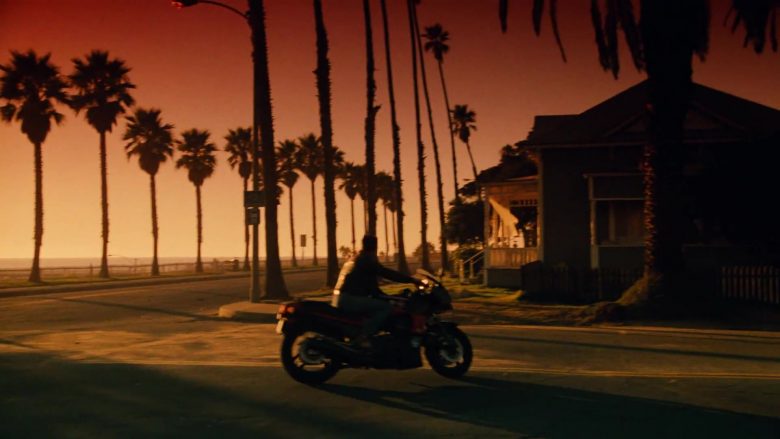 A person riding a motorcycle in front of a sunset